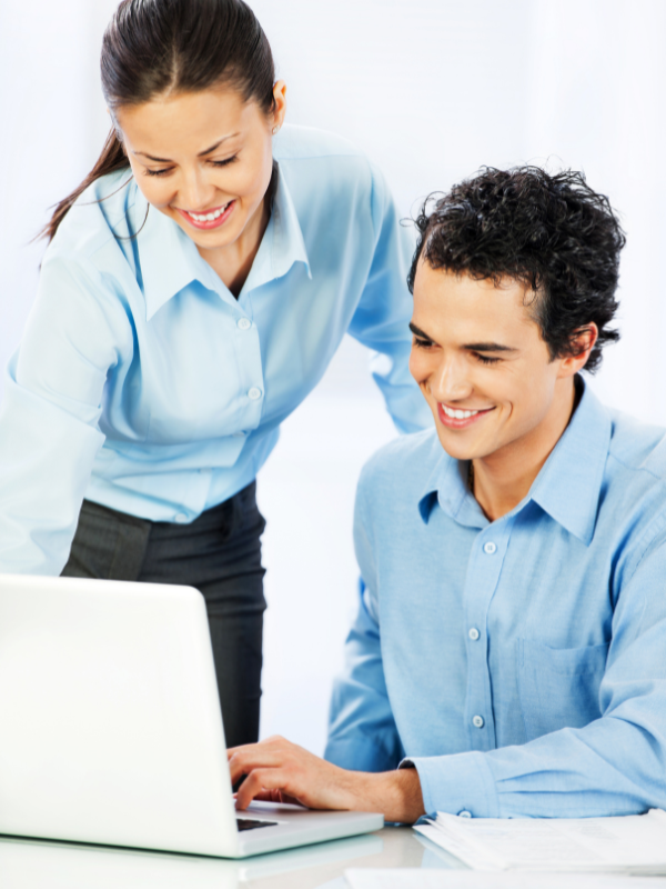Man and woman smiling and looking to laptop